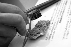 観察地点08で採取した石を観察する様子|2016年|宇都宮市大谷町 撮影=宇都宮美術館「石の街うつのみや」展 調査・撮影チーム (C)Utsunomiya Museum of Art